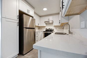 a kitchen with white cabinets and a stainless steel refrigerator at Citra Apartments LLC, California